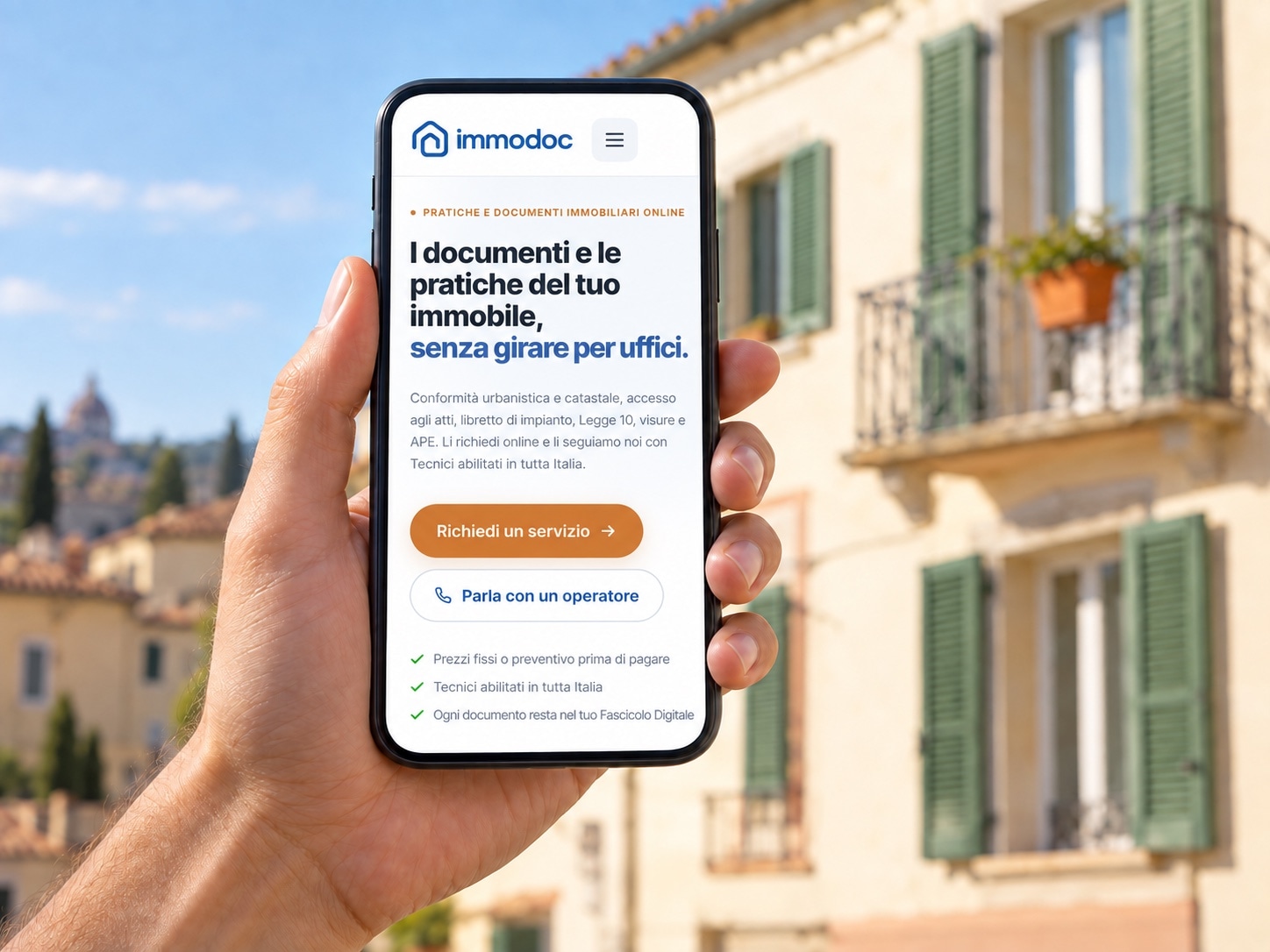 Una mano tiene uno smartphone con la home di Immodoc, davanti a una palazzina